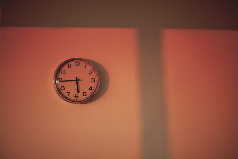 clock on the wall with orange light shining through a window