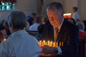 man handing out candles during service