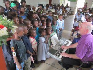 Bishop Sam Gray singing with children