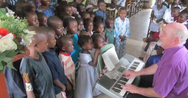 Bishop Sam Gray singing with children