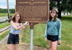 girls in front of Schoenbrunn schoolhouse sign