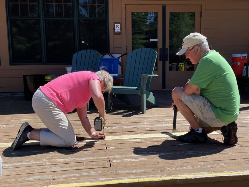 a couple drilling nails into a deck