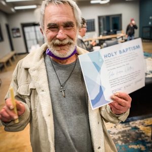 A place to belong image of man holding baptism certificate