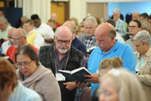 men sharing hymnal