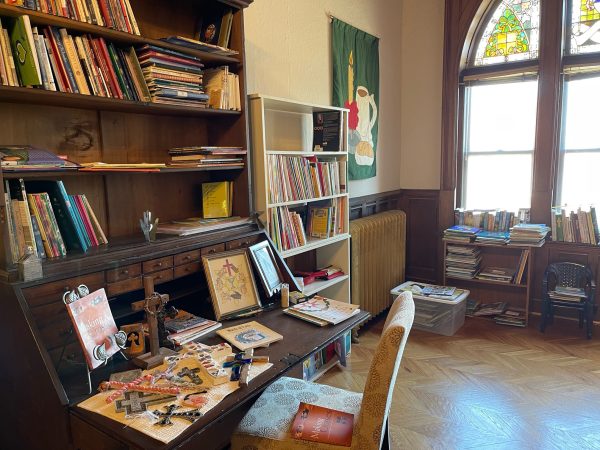 secretary desk with books and display of crosses and other bookshelves